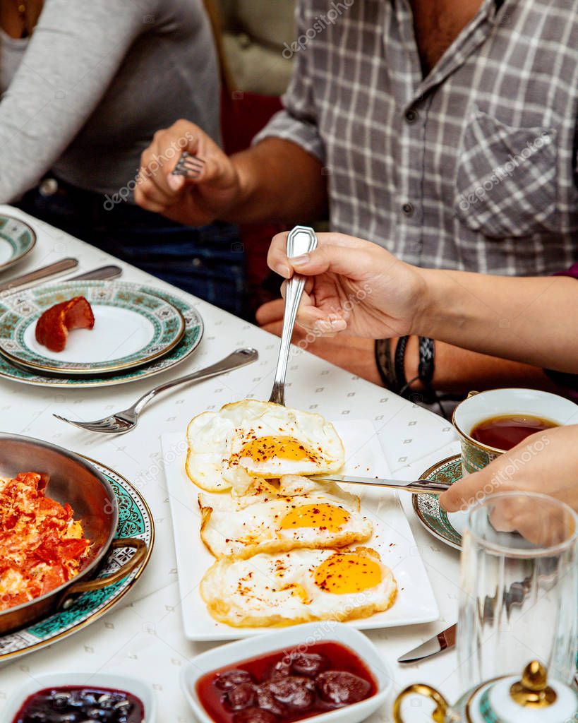 woman taking sunny side up egg served for breakfast