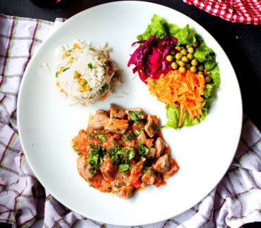 Pilav ve sebze soslu tavuk parçaları.