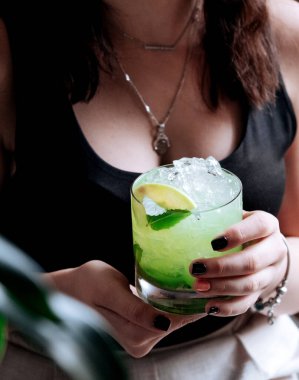 Kız elinde limonlu ve naneli mojito tutuyor.