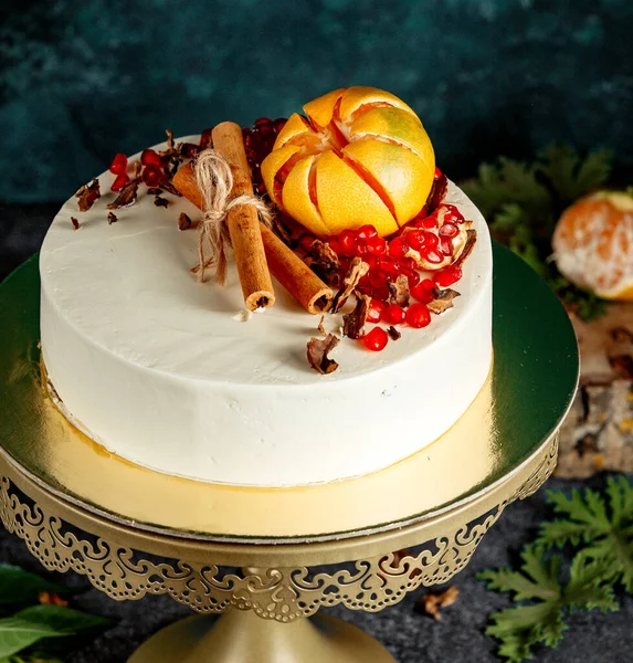 オレンジシナモンスティックとザクロで飾られた白いクリーミーなケーキ — ストック写真
