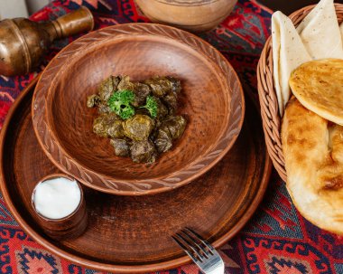 Yoğurtla servis edilen bir kase üzüm yaprağı dolması.