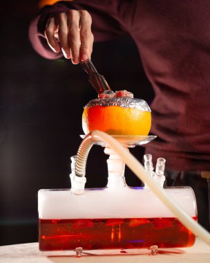 Greyfurt nargile için adam greyfurt üzerine kömür yakıyor.