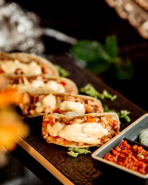 Biber ezmesiyle servis edilen mini tacoların yakın çekimi.