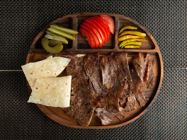beef steak slices served with flatbread tomato pickled peppers and cucumber