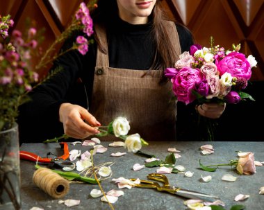 Elinde bir buket ponpon kız beyaz ve açık pembe güller tutan bir kadın.