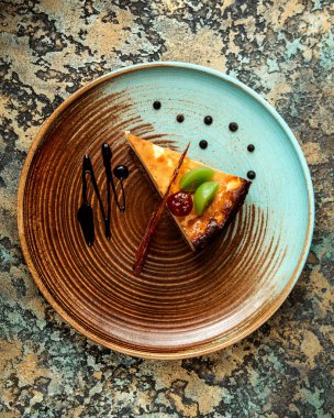 Bir dilim kivi soslu peynirli kek ve karamelize şeker.