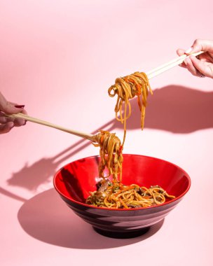 Kenar manzaralı udon kızarmış erişteyi et çanı biberli taze soğan soya sosu ve susamlı bir kasede karıştırır.