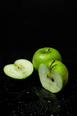 Siyah bir arkaplanda ikiye bölünmüş iki yeşil elma.