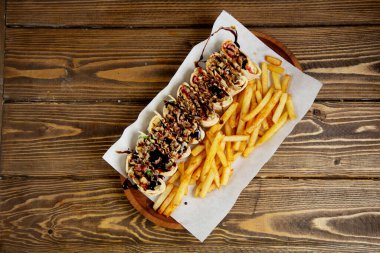 Pide ekmeğinde dilimlenmiş et rulosu ve patates kızartması.