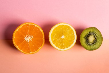 Yarısı dilimlenmiş portakallı limon ve kivi masada.