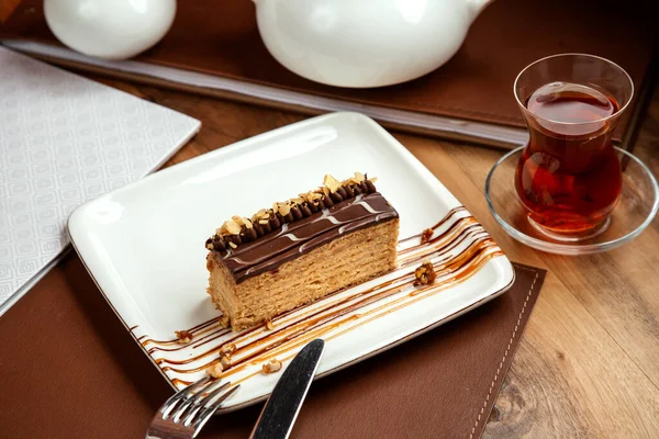 サイドビューケーキテーブルの上にチョコレートナッツと紅茶と層状の蜂蜜ケーキ — ストック写真