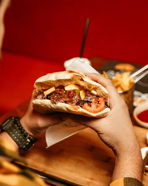 man eats doner in bread with meat tomatoes and french fries