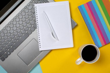 bir fincan kahve ile dizüstü bilgisayar ve not defteri