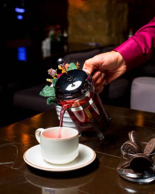 Adam fincana meyve çayı döker.