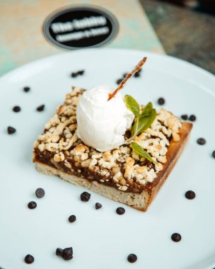 Yanında dondurma ve çikolata parçacıkları olan bir pasta.