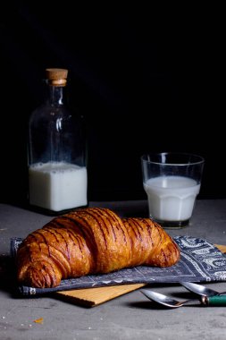 Üzerinde çilek şurubu ve bir bardak süt olan hava kruvasanı.