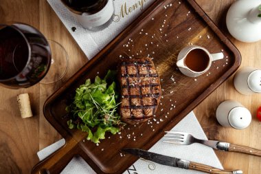 Biftek ızgara kırmızı et, marul salatası tuz ve bir bardak kırmızı şarap.