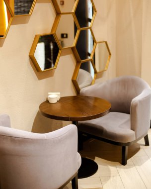 Kahve masaları, koltuklar ve aynalar duvarda.