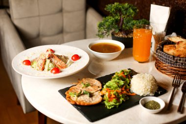 Salata, pirinç çorbası ve sezar salatayla servis edilmiş tavuk bifteği.