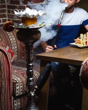 Masasında kulüp sandviçi olan shisha 'lı adam.