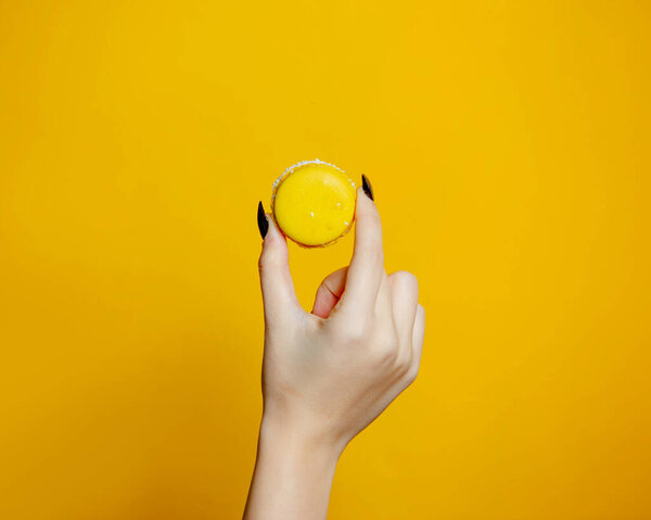 woman holds macaroon in hand