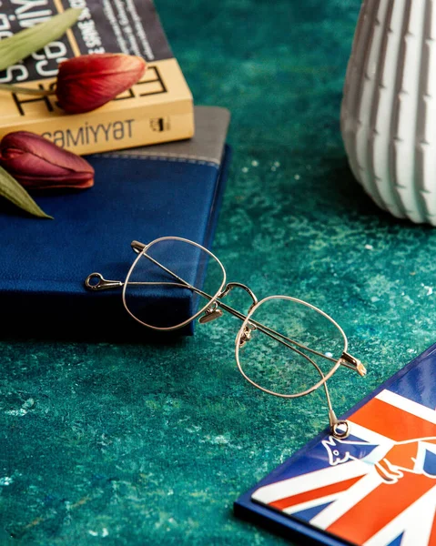 side view thin rim glasses with books and tulips on the table