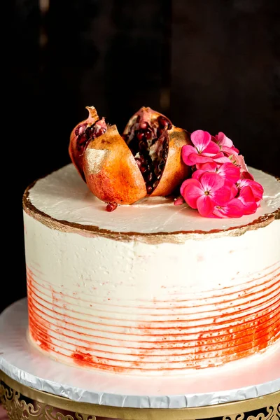 ザクロと花で装飾されたクリーミーなケーキの終わり — ストック写真