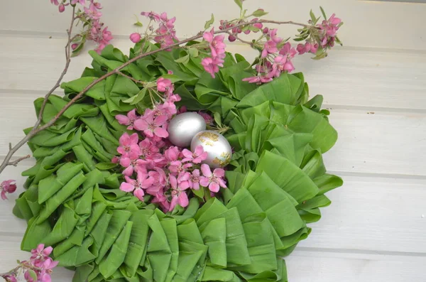 Beautiful festive wreath of green leaves with pink flowers and silver eggs. easter plants — Stock Photo, Image