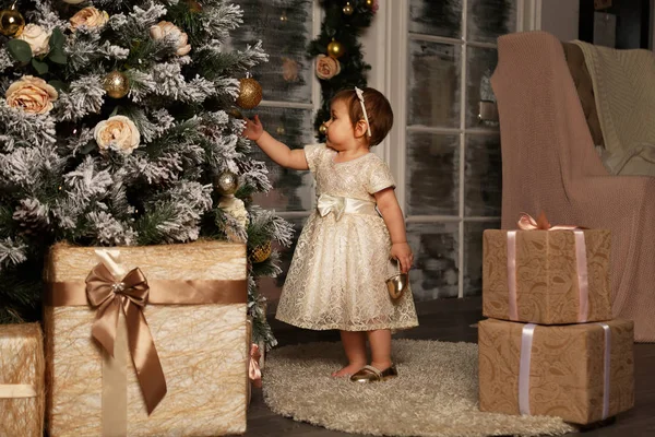 Küçük, güzel bir kız, Noel için hediyeler alıyor, ve Noel ağacının yanında güzel bir altın elbiseyle dilek diliyor.