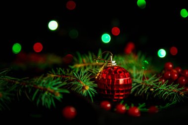 Noel oyuncakları, üzerinde yeşil Noel ağacı olan karanlık arka planda ışıklar