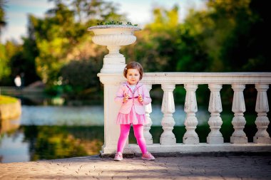 Mavi gözlü, küçük, güzel bir kız. Pembe elbisesiyle parkta yürüyor.