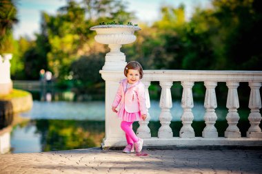 Mavi gözlü, küçük, güzel bir kız. Pembe elbisesiyle parkta yürüyor.