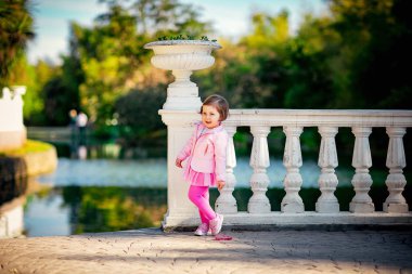 Mavi gözlü, küçük, güzel bir kız. Pembe elbisesiyle parkta yürüyor.