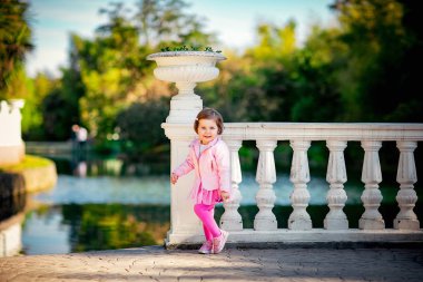 Mavi gözlü, küçük, güzel bir kız. Pembe elbisesiyle parkta yürüyor.