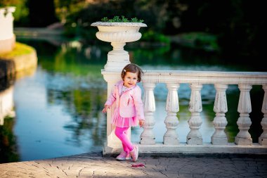 Mavi gözlü, küçük, güzel bir kız. Pembe elbisesiyle parkta yürüyor.