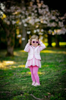 Mavi gözlü, küçük, güzel bir kız. Pembe elbisesiyle parkta yürüyor.