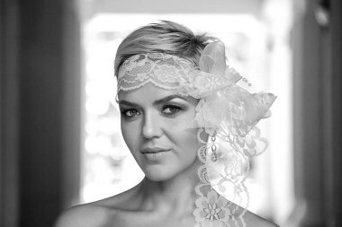 Güzel, genç bir gelin, eski moda bir elbise içinde, beyaz, elinde çiçeklerle poz veriyor.