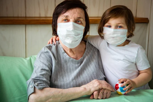an adult woman, a retired grandmother, with a granddaughter , and wearing a medical mask, is in home quarantine, and playing because of COVID-19