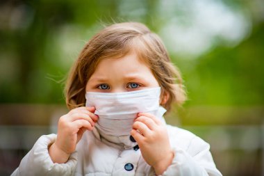 Küçük kız tıbbi bir maske takıyor.