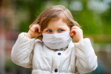 Küçük kız tıbbi bir maske takıyor.