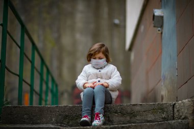 Küçük kız tıbbi bir maske takıyor.