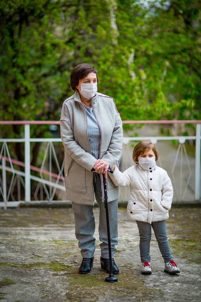 Uma Menina Sua Avó Usando Máscaras Médicas Caminham Uma Rua — Fotografia de Stock