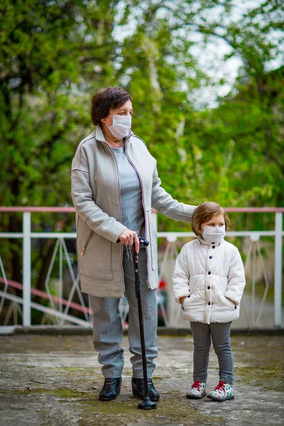 Uma Menina Sua Avó Usando Máscaras Médicas Caminham Uma Rua — Fotografia de Stock