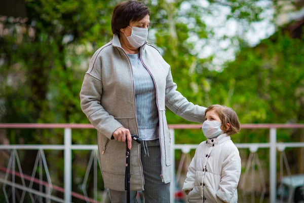 Uma Menina Sua Avó Usando Máscaras Médicas Caminham Uma Rua — Fotografia de Stock