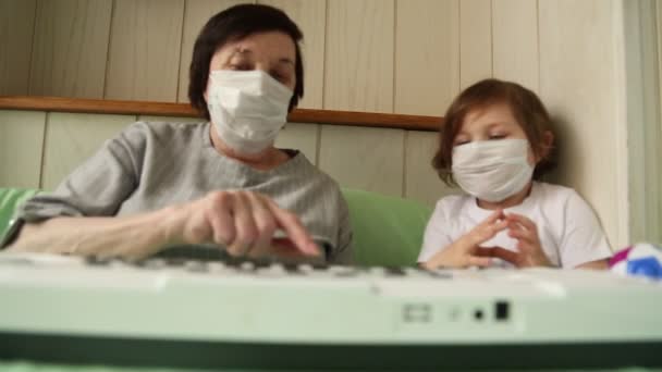 Une femme adulte, avec une petite fille, apprenant à jouer du piano, pendant une quarantaine à domicile, en raison de la pandémie de covide-19 — Video