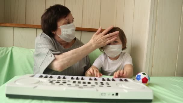 Een volwassen vrouw, met een klein meisje, die piano leert spelen, tijdens een thuisquarantaine, als gevolg van de hevige-19 pandemie — Stockvideo