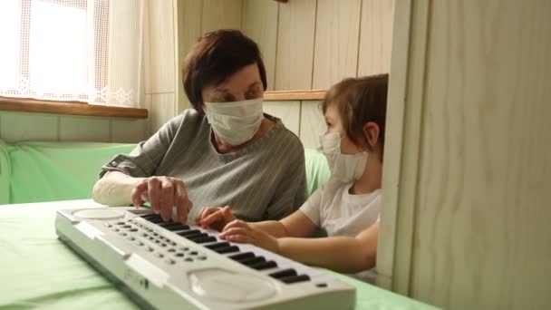 Взрослая женщина, с маленькой девочкой, учится играть на пианино, во время домашнего карантина, из-за пандемии ковида-19 — стоковое видео