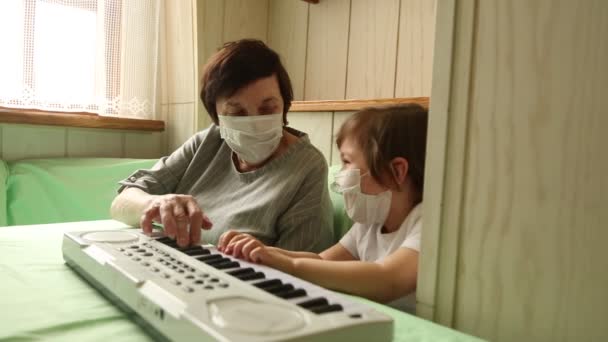 Une femme adulte, avec une petite fille, apprenant à jouer du piano, pendant une quarantaine à domicile, en raison de la pandémie de covide-19 — Video