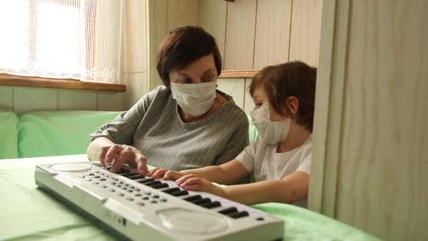 Yetişkin bir kadın, küçük bir kızla birlikte, ev karantinasında piyano çalmayı öğreniyor, covid-19 salgını yüzünden. — Stok video