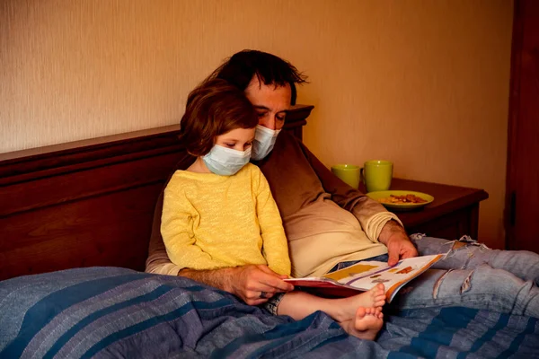 daddy and daughter in medical masks, studying art photography, at home during quarantine, due to the covid-19 pandemic
